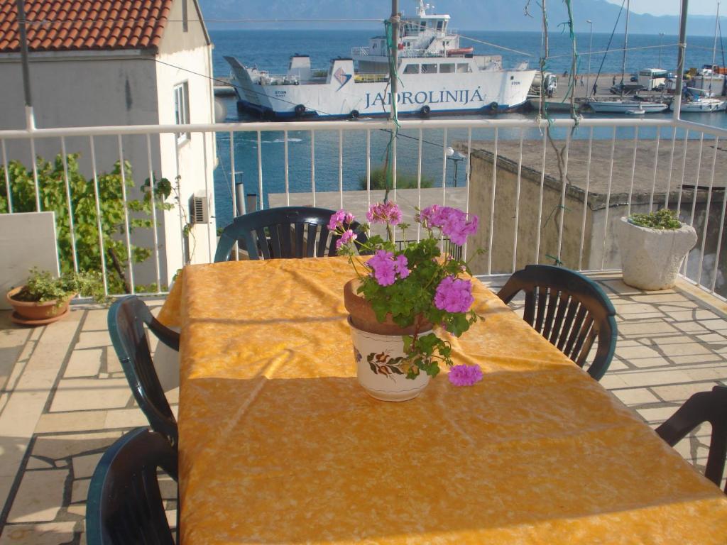 a table with flowers on a balcony with a cruise ship at Apartments San Giorgio in Sućuraj
