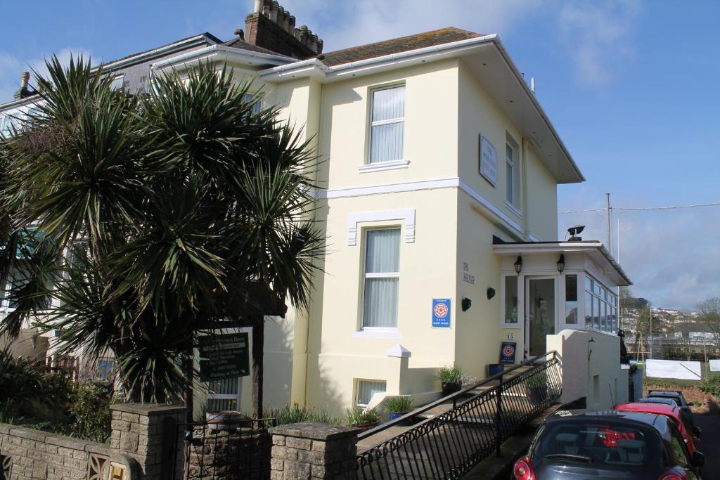 a white house with a palm tree in front of it at The Ashleigh in Paignton