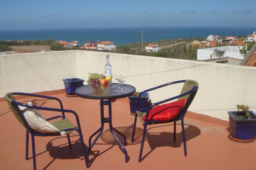 a table with two chairs and a bottle of wine on a balcony at Bela Vista in Lourinhã