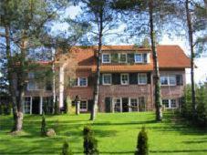 a large brick house with trees in front of it at Das kleine Hotel am Park Garni in Bispingen