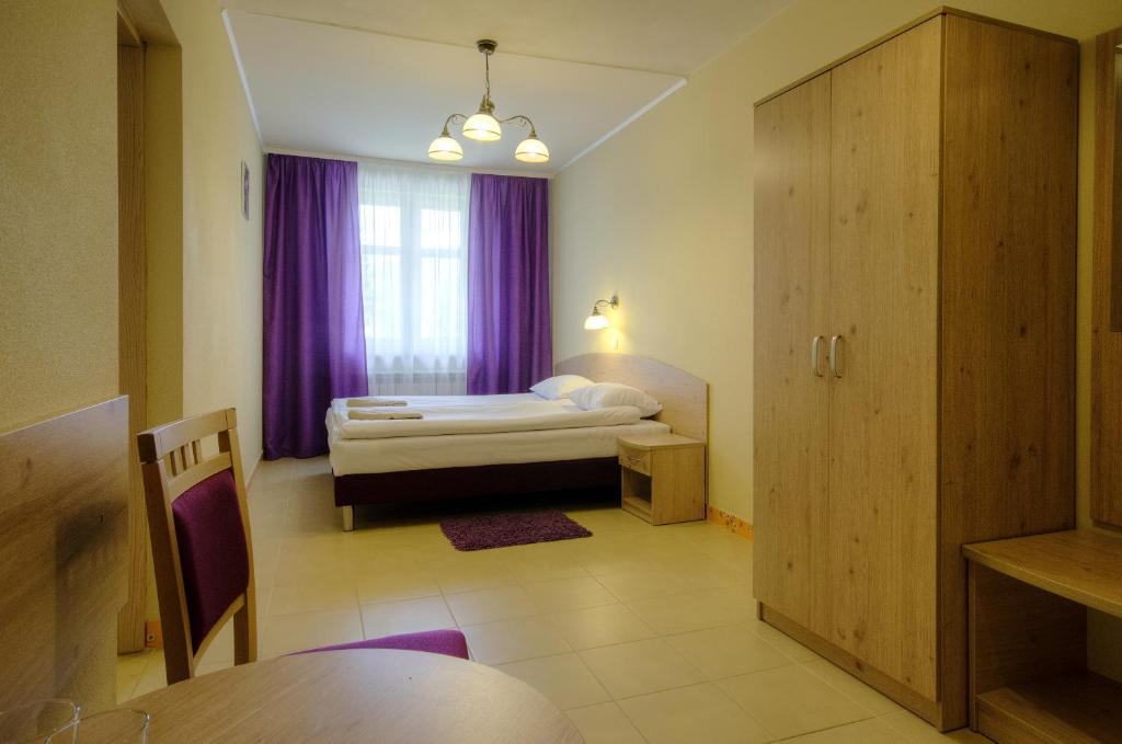 ヴィスワにあるDworek nad Wisłąのベッドルーム1室(ベッド1台付)、紫色のカーテン付きの窓が備わります。