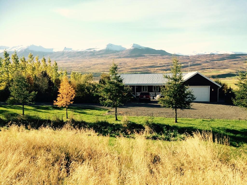 una casa en un campo con montañas en el fondo en Ásar Guesthouse en Eyjafjaroarsveit