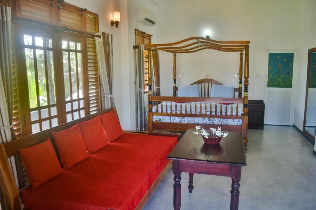 a living room with a red couch and a bed at Ravi Villa Hikkaduwa in Hikkaduwa