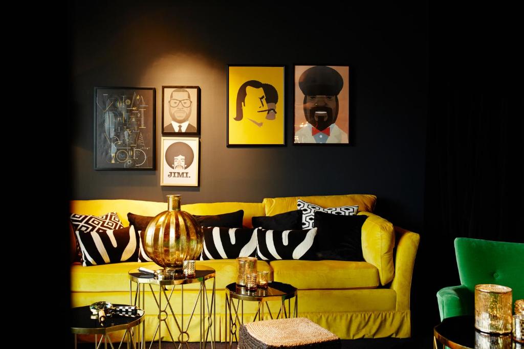 un salon avec un canapé jaune et des photos sur le mur dans l'établissement Hotel Friends, à Cologne