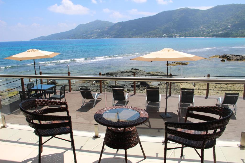 d'une terrasse avec des chaises et des tables et une vue sur l'océan. dans l'établissement Surfers Cove Apartments, à Bel Ombre