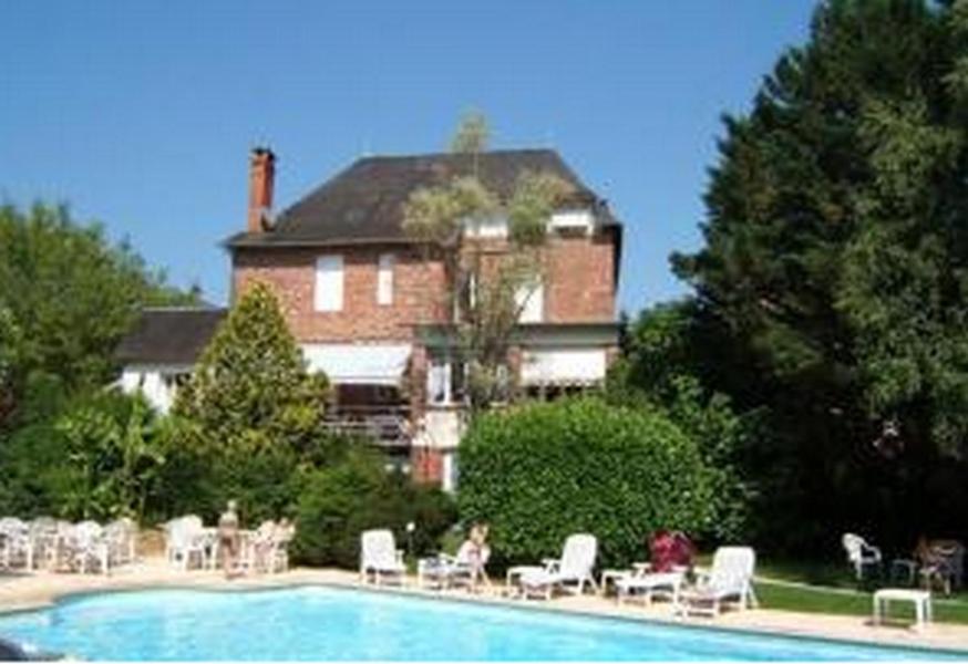 a large house with a swimming pool in front of a house at LogisHotels Le Relais du Quercy in Meyssac