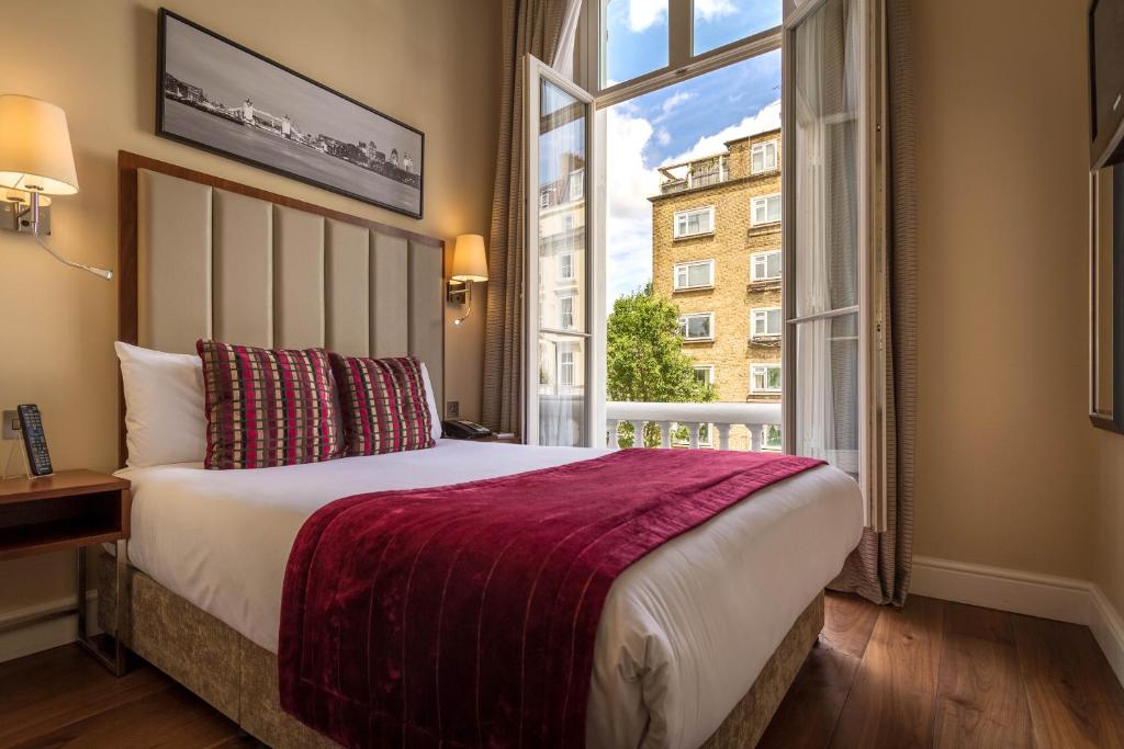 ein Schlafzimmer mit einem Bett und einem großen Fenster in der Unterkunft The Belgrave Hotel in London