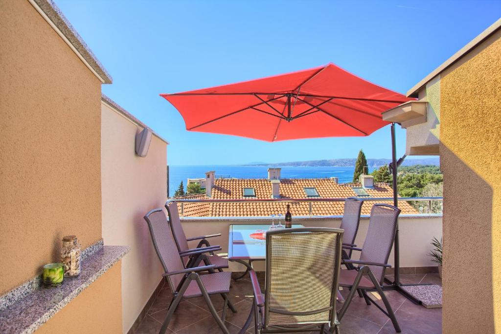 a patio with a table and a red umbrella at Apartments VALL in Krk