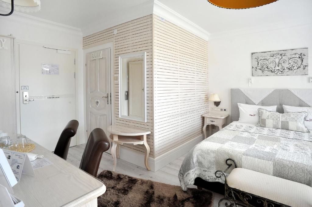 Bright coastal-style double bedroom with patterned quilt, bedside table, desk and cushioned chairs, calm ambience