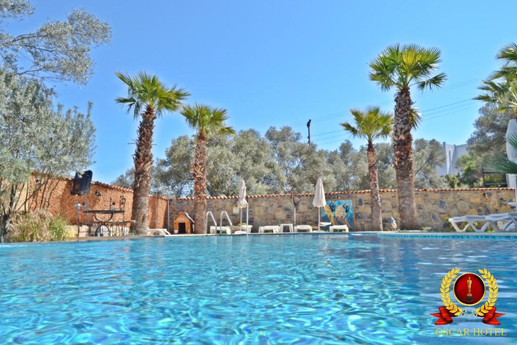a pool at the resort with palm trees at Bodrum Oscar Hotel in Torba