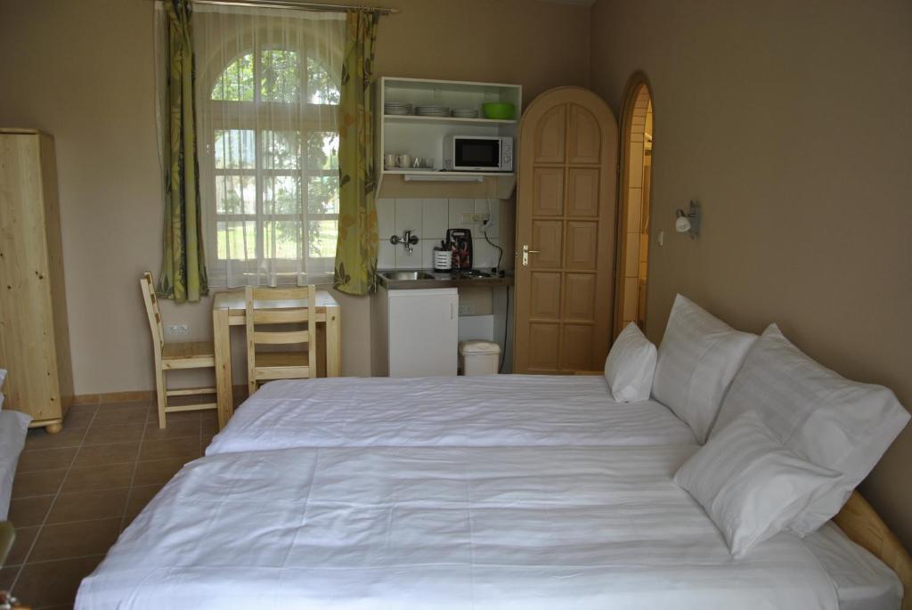 シャールヴァールにあるSárvárfürdő Apartmanházのベッドルーム(大きな白いベッド1台付)、キッチンが備わります。