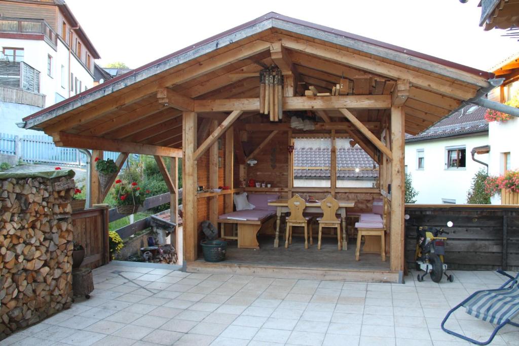 a wooden pavilion with a table and chairs on a patio at Pension Mühlbauer in Lam
