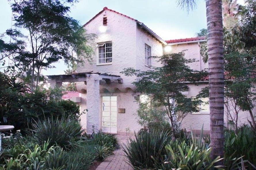 a white house with a palm tree in front of it at MiCasa SuCasa Manor in Pretoria