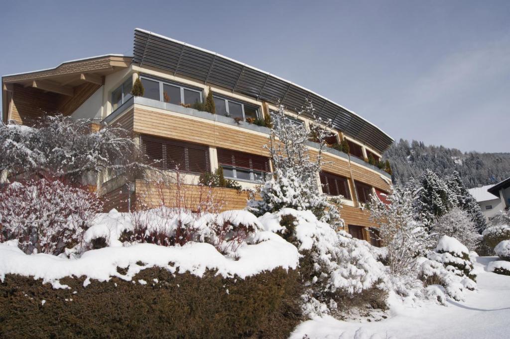 a building covered in snow with bushes and trees at Hotel Sonnenheim in Bad Kleinkirchheim