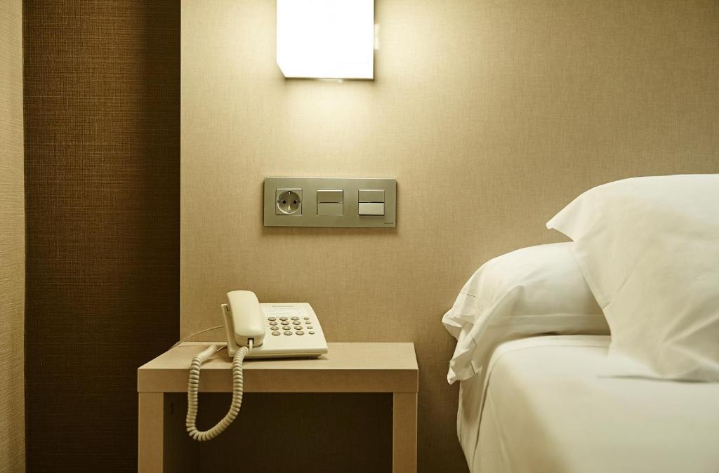 a hotel room with a phone on a table next to a bed at Hotel Parma in San Sebastián
