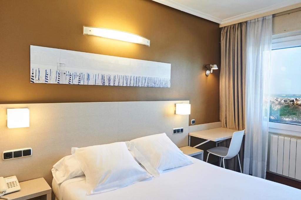 a hotel room with a bed and a desk and a window at Hotel Parma in San Sebastián