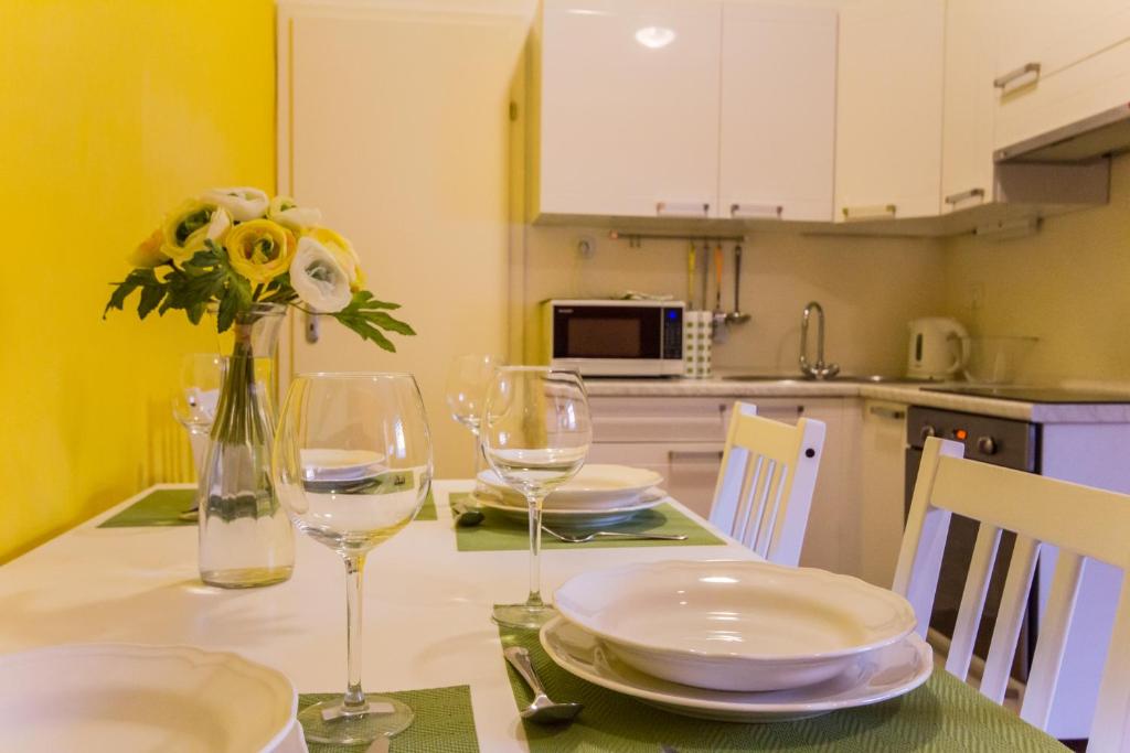 a table with plates and glasses and a vase with flowers at Apartment Bright & Light in Ljubljana
