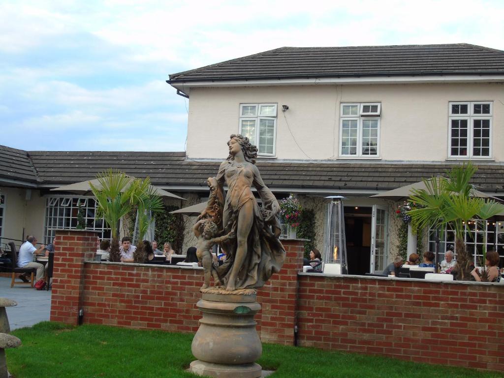 uma estátua de uma mulher em pé em frente a um edifício em Littleover Lodge Hotel em Derby