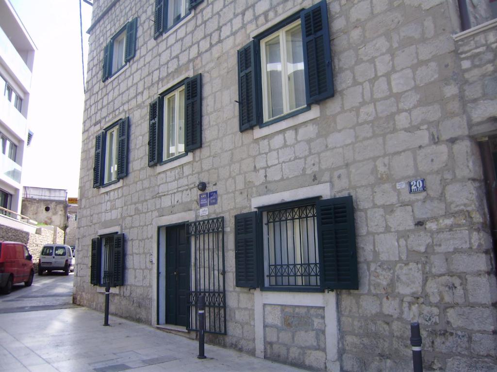 ein Steingebäude mit schwarzen Rollläden auf einer Straße in der Unterkunft Anthea Rooms in Split