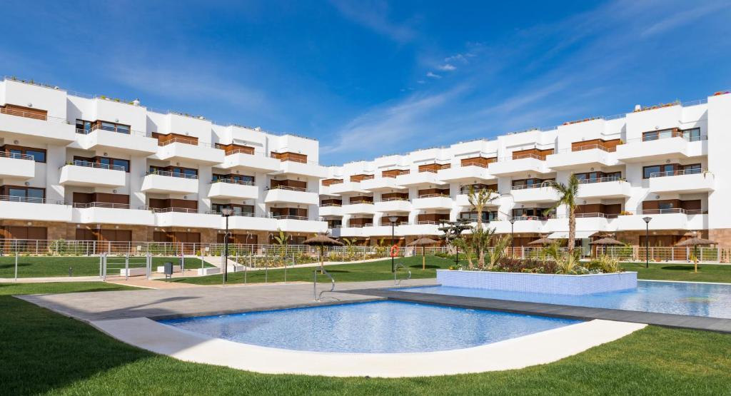 プレヤス・デ・オリフエラにあるTerrazas de Campoamor by Mar Holidaysのアパートメントの建物の正面にプールがあります。