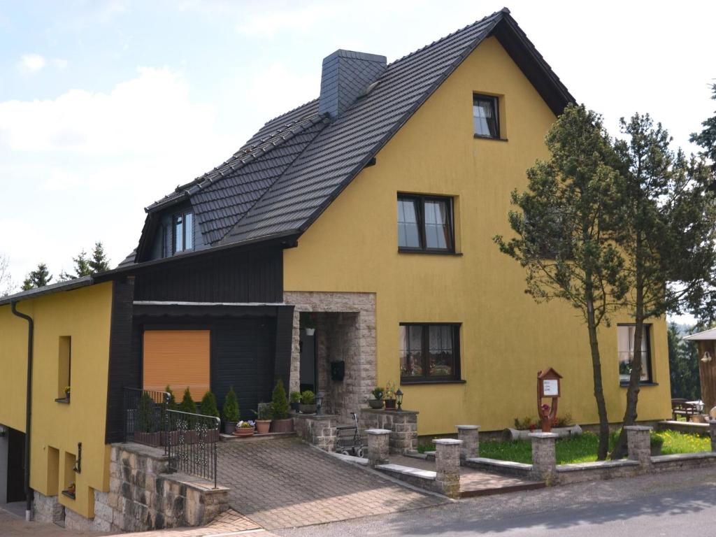 een geel huis met een zwart dak bij Cosy apartment in Frauenwald near forest in Frauenwald