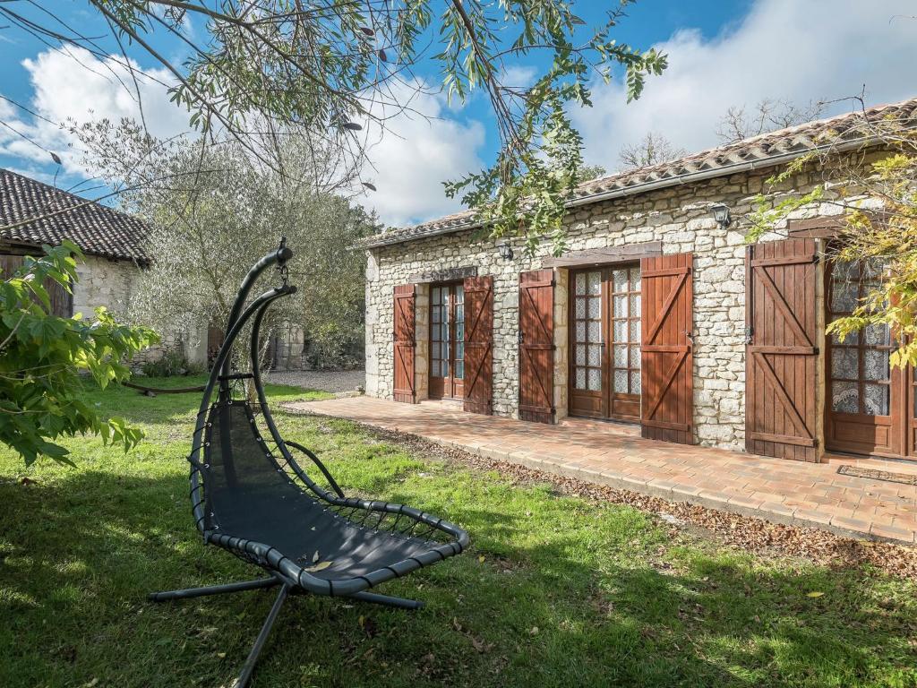 uma cadeira preta sentada na relva em frente a um edifício em Charming holiday home with pool em Monbazillac