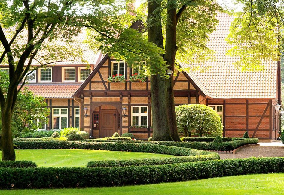 dom z zielonym dziedzińcem z drzewami i krzakami w obiekcie Heidehotel Waldhütte w mieście Telgte