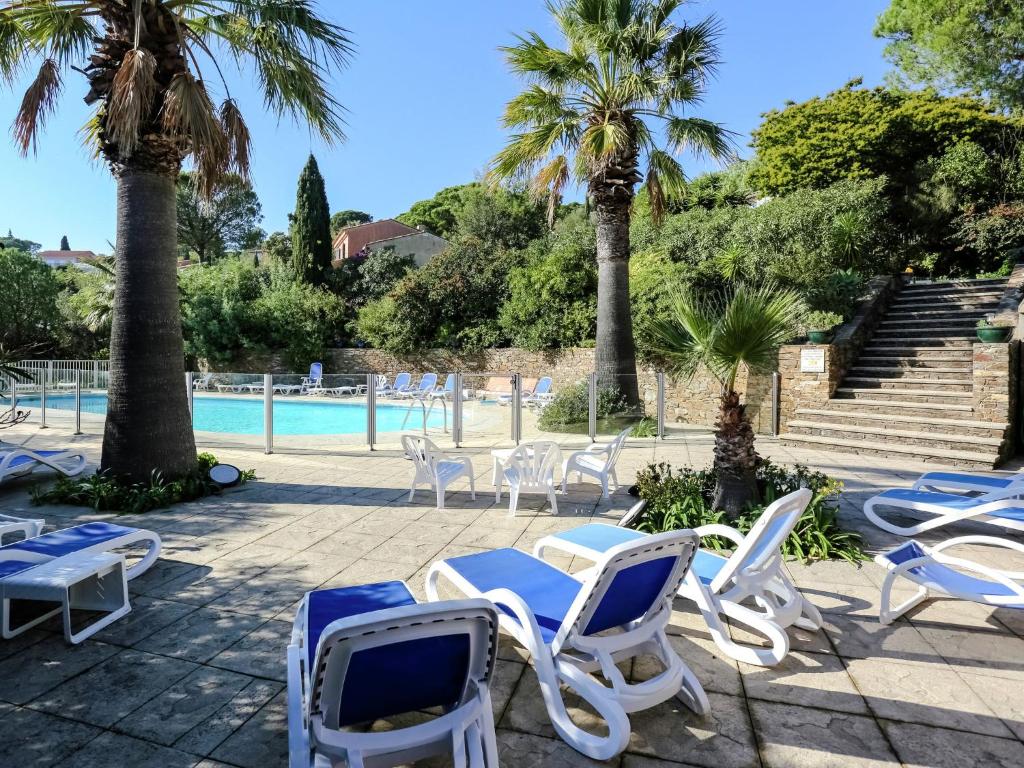 a group of chairs and a swimming pool with palm trees at Boutique Holiday Home in Bormes les Mimosas with Pool in Bormes-les-Mimosas