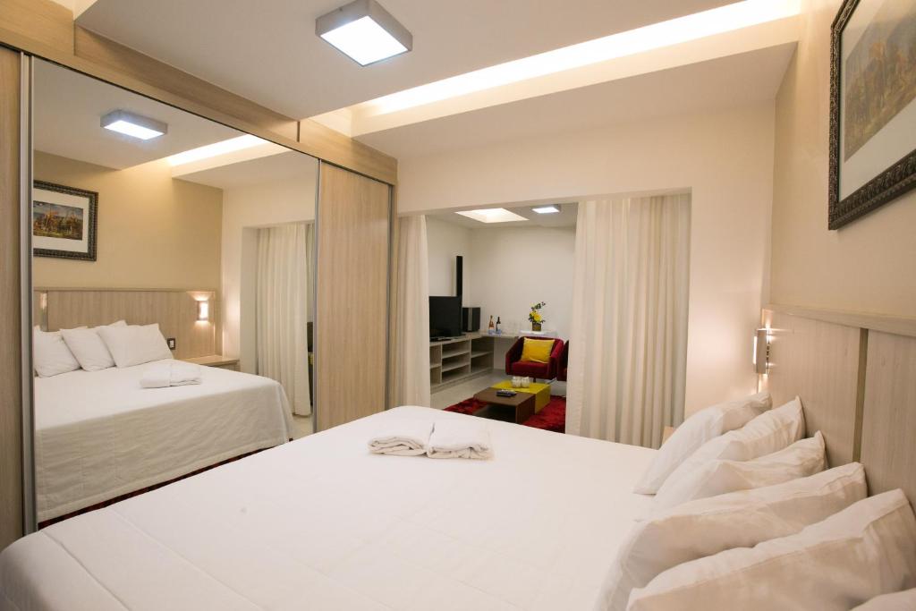 a hotel room with two beds and a mirror at Hotel Colombo in Barra do Garças