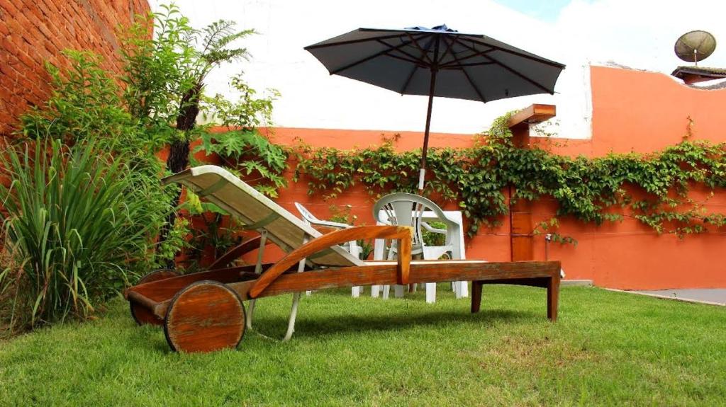 a bench with an umbrella in the grass at Pousada da Ju in Guarujá