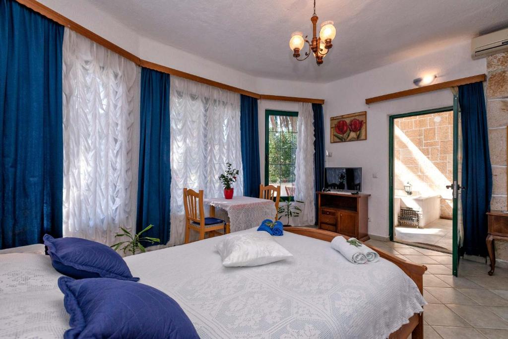 a bedroom with two beds with blue curtains and a table at Apartments Villa Domus Marini in Hvar