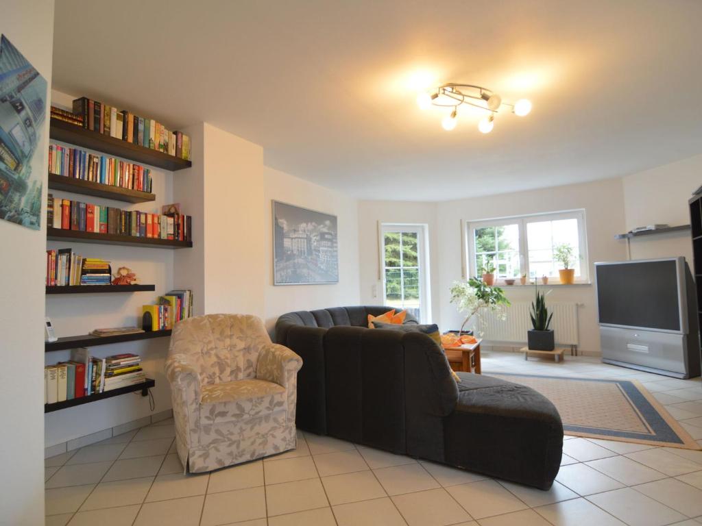 ein Wohnzimmer mit einem Sofa, einem Stuhl und einem TV in der Unterkunft Apartment in Ulmen near the lake in Ulmen