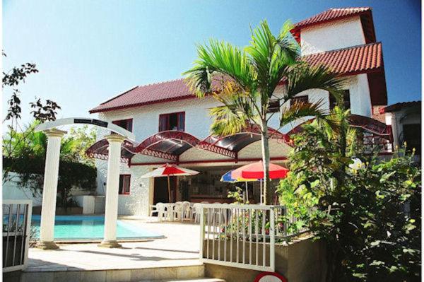 a house with a pool and a palm tree in front of it at Residencial Sol e Mar de Floripa in Florianópolis