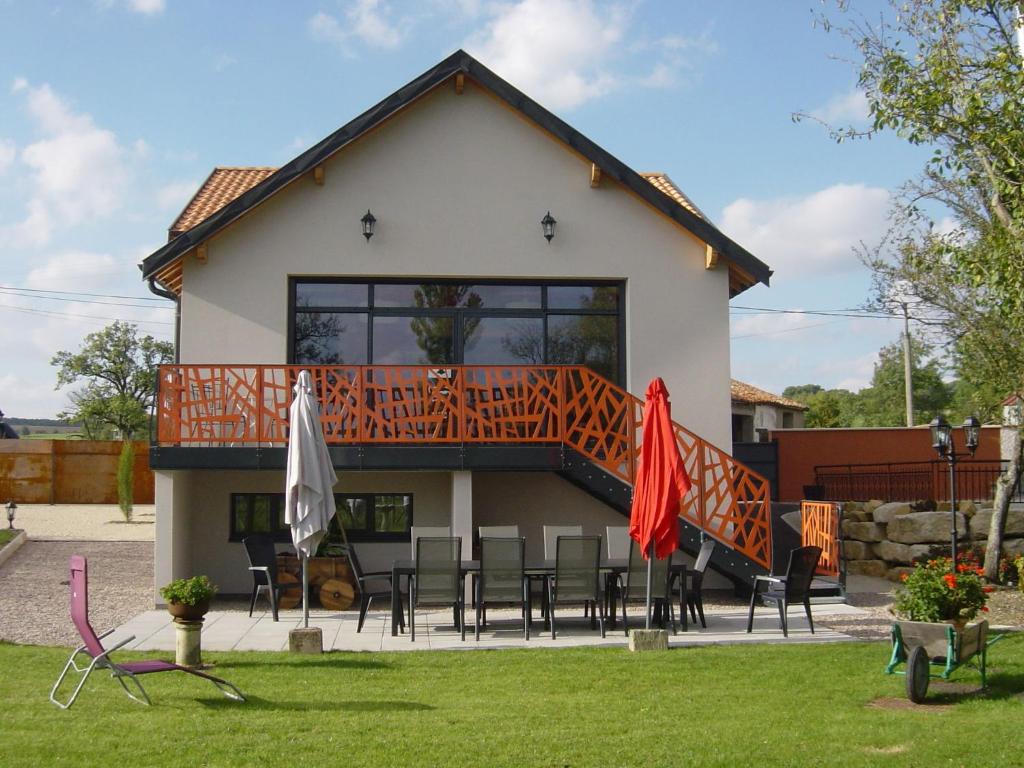 ein Haus mit einer Terrasse mit Stühlen und Sonnenschirmen in der Unterkunft Character house with pool jacuzzi in Gondrecourt-le-Château