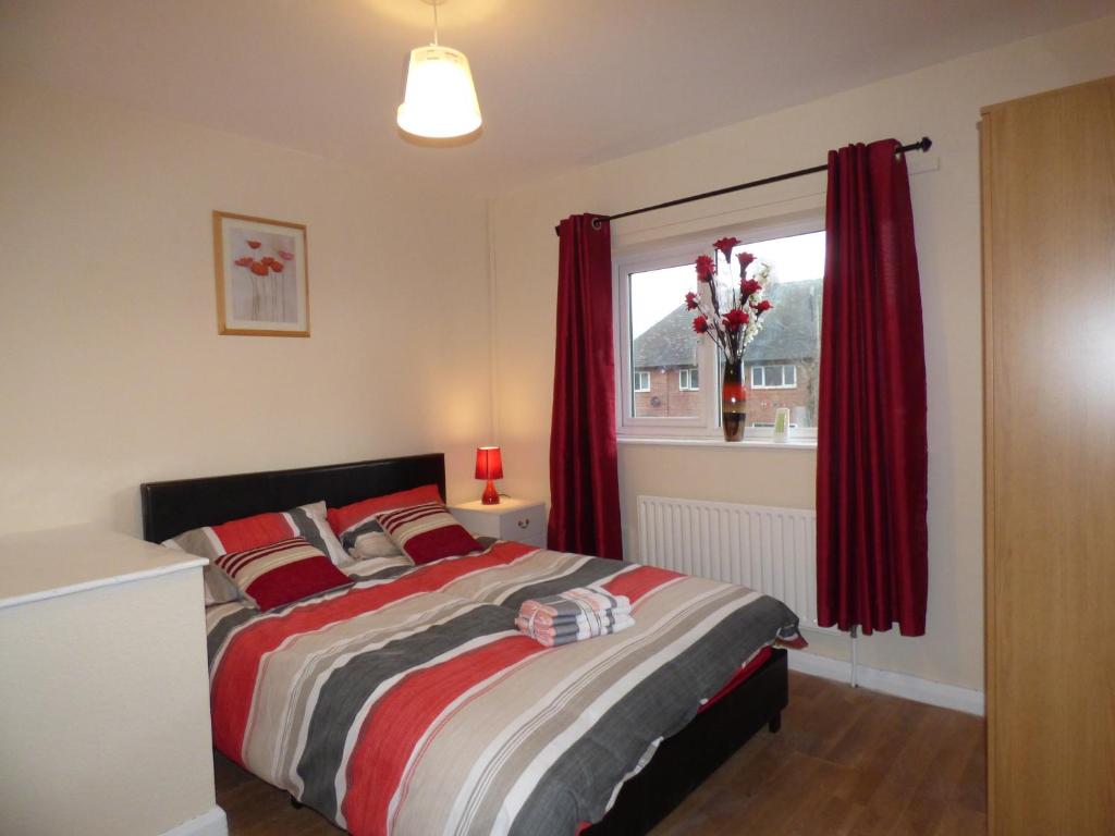 um quarto com uma cama com cortinas vermelhas e uma janela em Beckley House em Nottingham