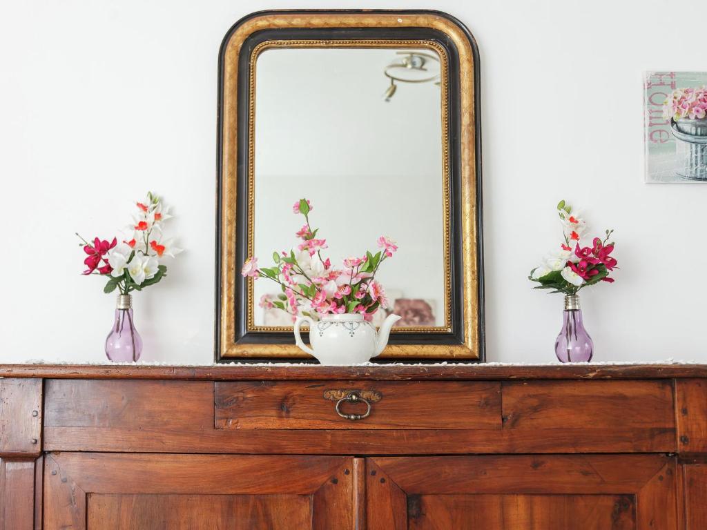 a mirror on top of a dresser with flowers in vases at Amazing Holiday Home in Cazals with Terrace in Cazals