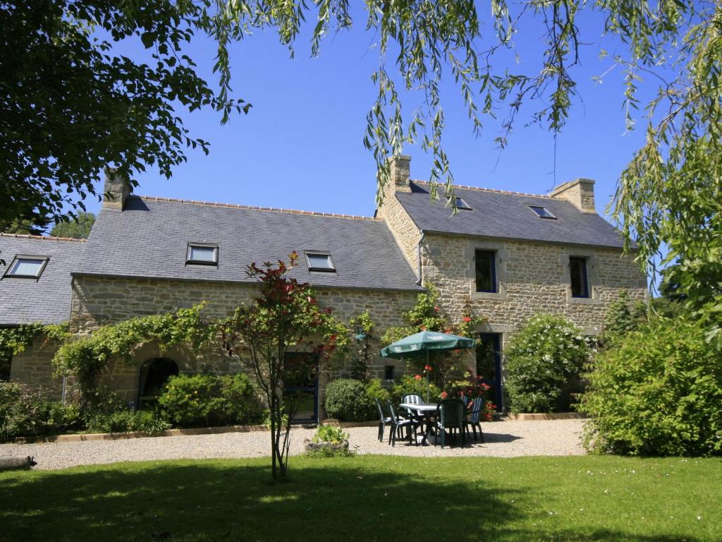 Cette grande maison en pierre comprend une table et des chaises. dans l'établissement Chalet in Plounéour-Trez by Seaside Bay, à Plounéour-Trez