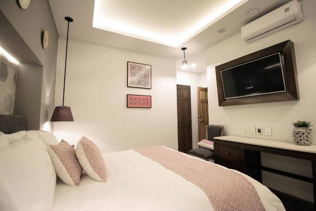 Schlafzimmer mit einem Bett und einem Flachbild-TV in der Unterkunft Casa Rosa Gran Hotel Boutique in Puebla