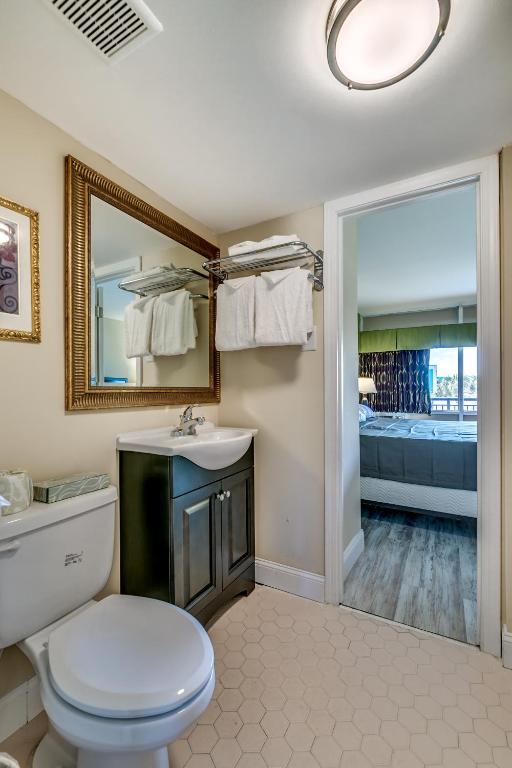 a bathroom with a toilet and a sink and a mirror at Beachcomber Inn & Suites in Myrtle Beach