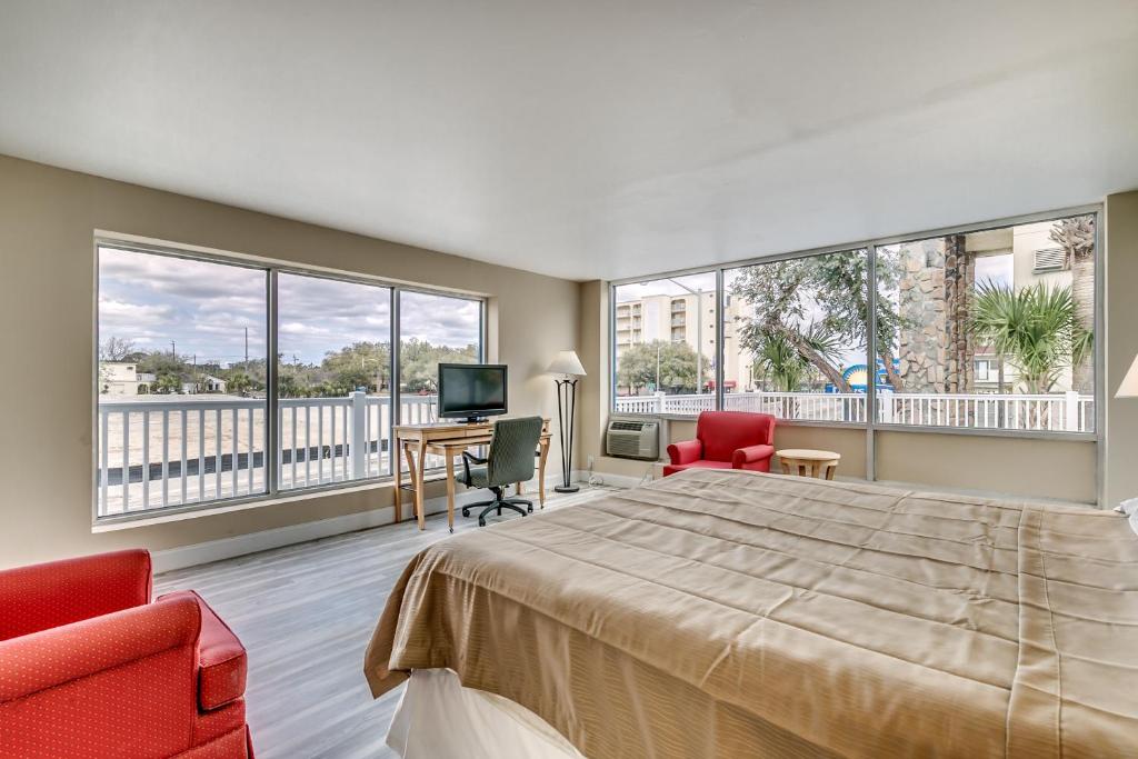 a bedroom with a large bed and two chairs and a desk at Beachcomber Inn & Suites in Myrtle Beach