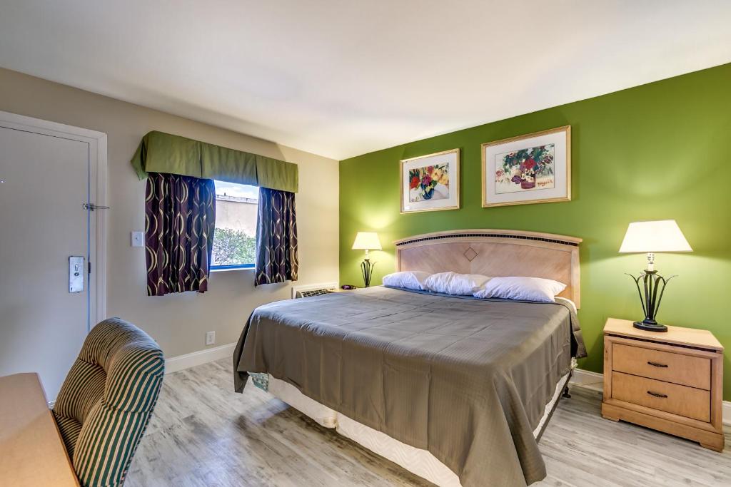a bedroom with green walls and a bed and a table at Beachcomber Inn & Suites in Myrtle Beach