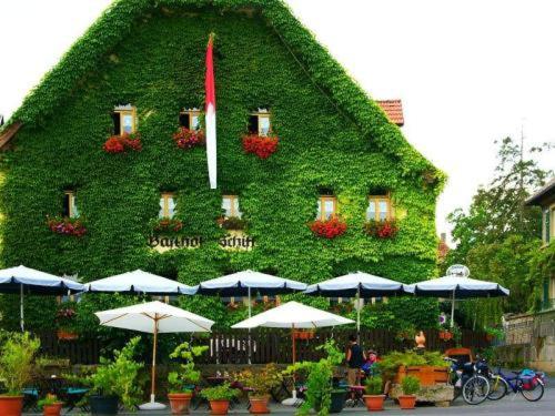 ein Gebäude mit Pflanzen und Sonnenschirmen davor in der Unterkunft Hotel-Gasthof-Schiff in Winterhausen