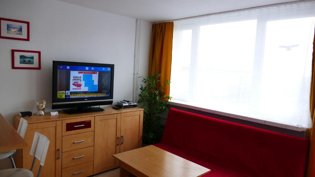 グダニスクにあるApartamenty Olimpのリビングルーム(テレビ、赤いソファ、窓付)