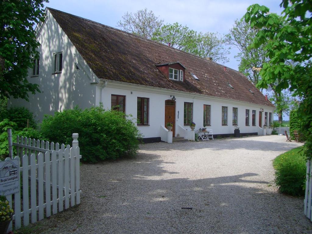a white building with a brown roof and a fence at Bed & Breakfast Vragerups Gård in Lomma