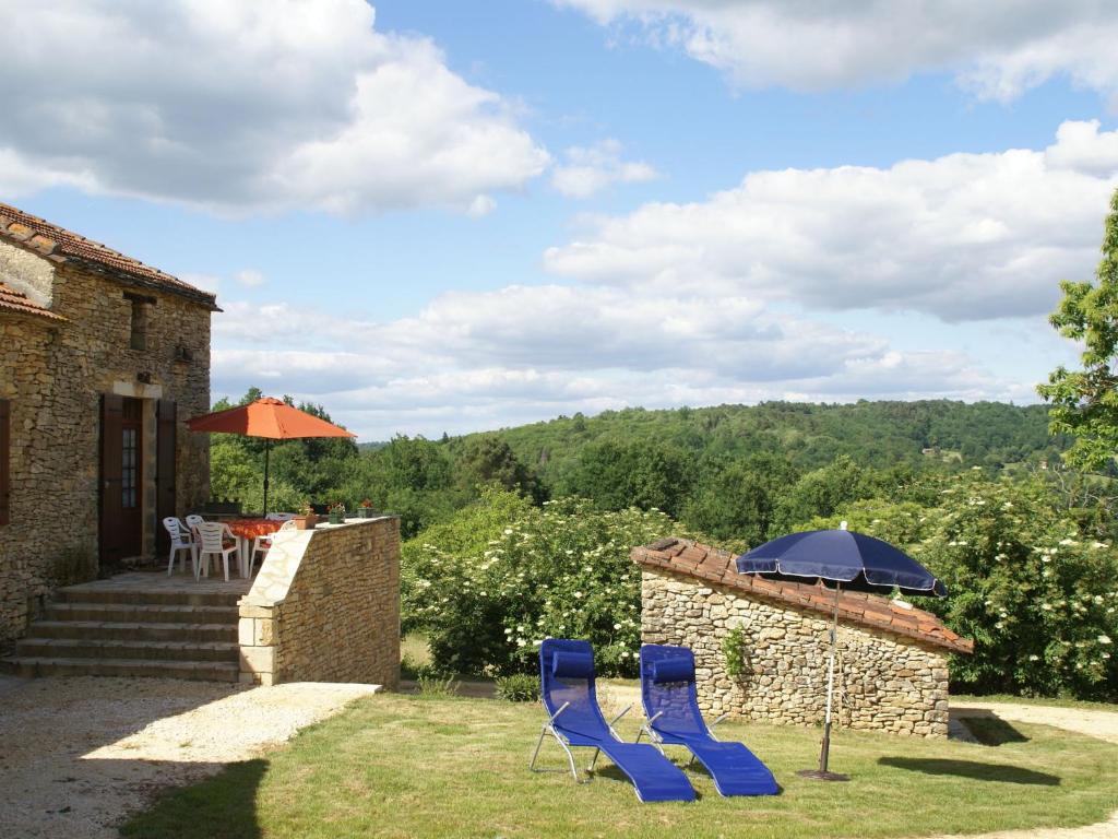 a patio with two blue chairs and an umbrella at Heavenly holiday home with pool in Villefranche-du-Périgord