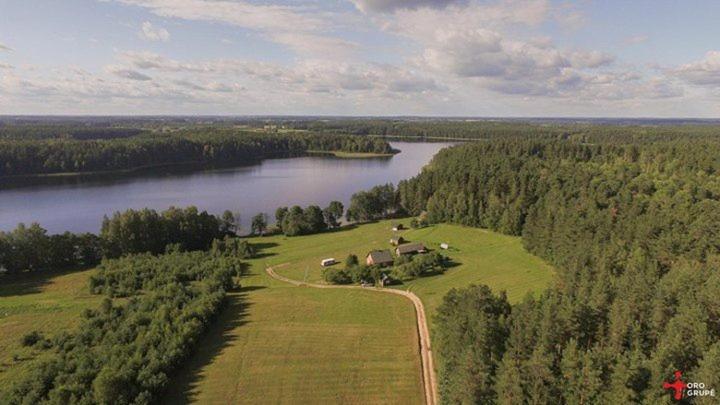an aerial view of a house on a field next to a lake at Kaimo Turizmo Sodyba Šniūrai in Mindūnai