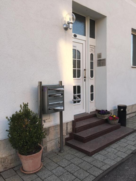 une maison blanche avec une porte, des escaliers et une plante dans l'établissement Ferienwohnung TINA, à Naumbourg