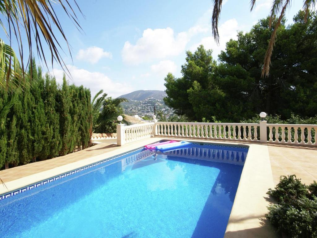 Nice villa in Moraira with private pool and lots of privacy في مورايرا: مسبح ازرق بسياج ابيض واشجار