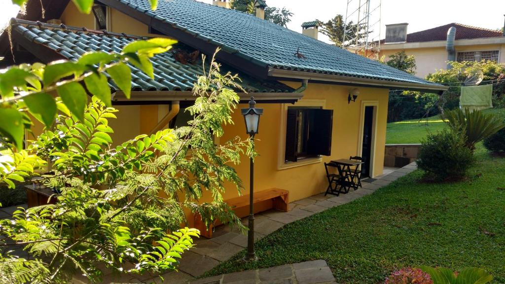 una casa amarilla con una mesa en un patio en Chalé no Centro de Canela, en Canela