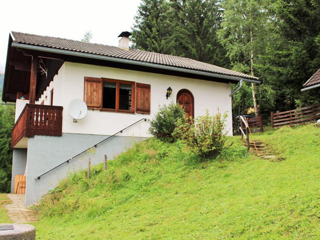 uma pequena casa branca numa colina relvada em Holiday home in Arriach near Lake Ossiach em Arriach